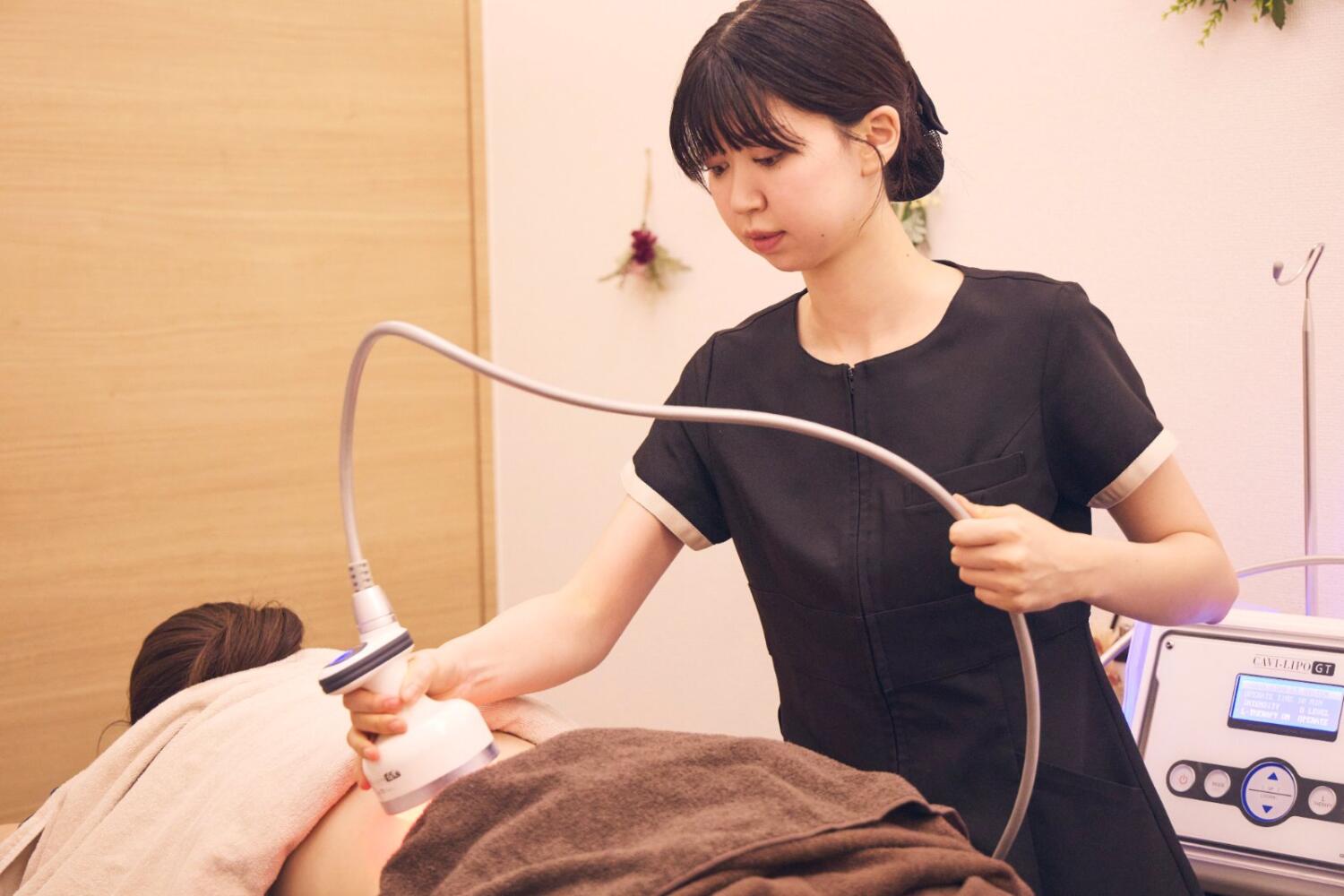 サロンで女性スタッフが機器を使って施術する様子