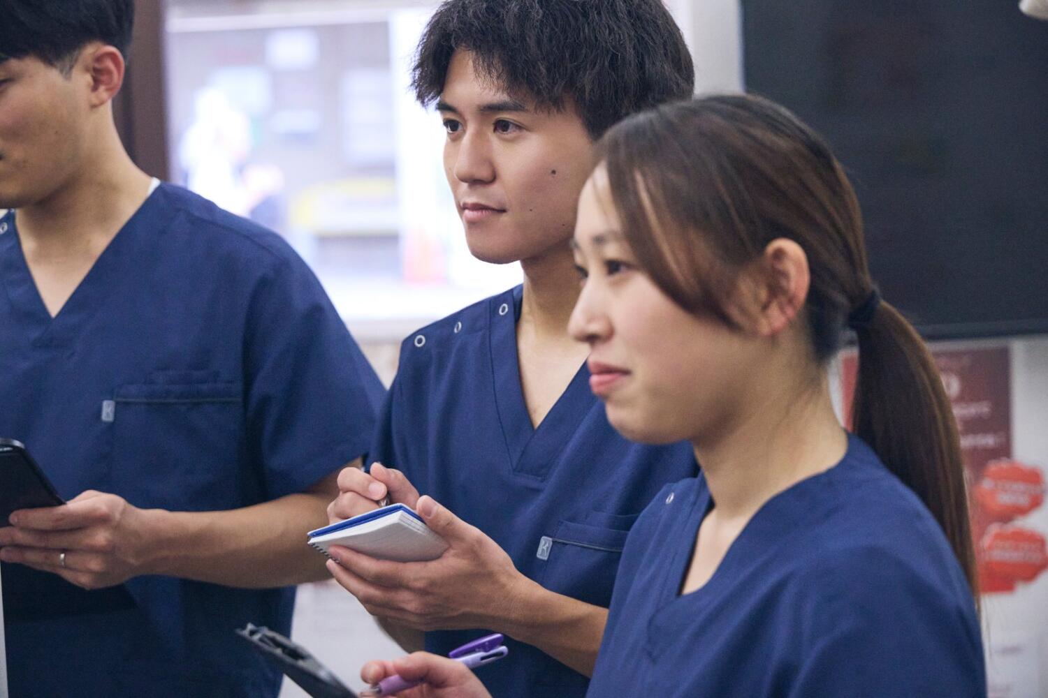 メモ帳を手に真剣に話を聞く若手スタッフ