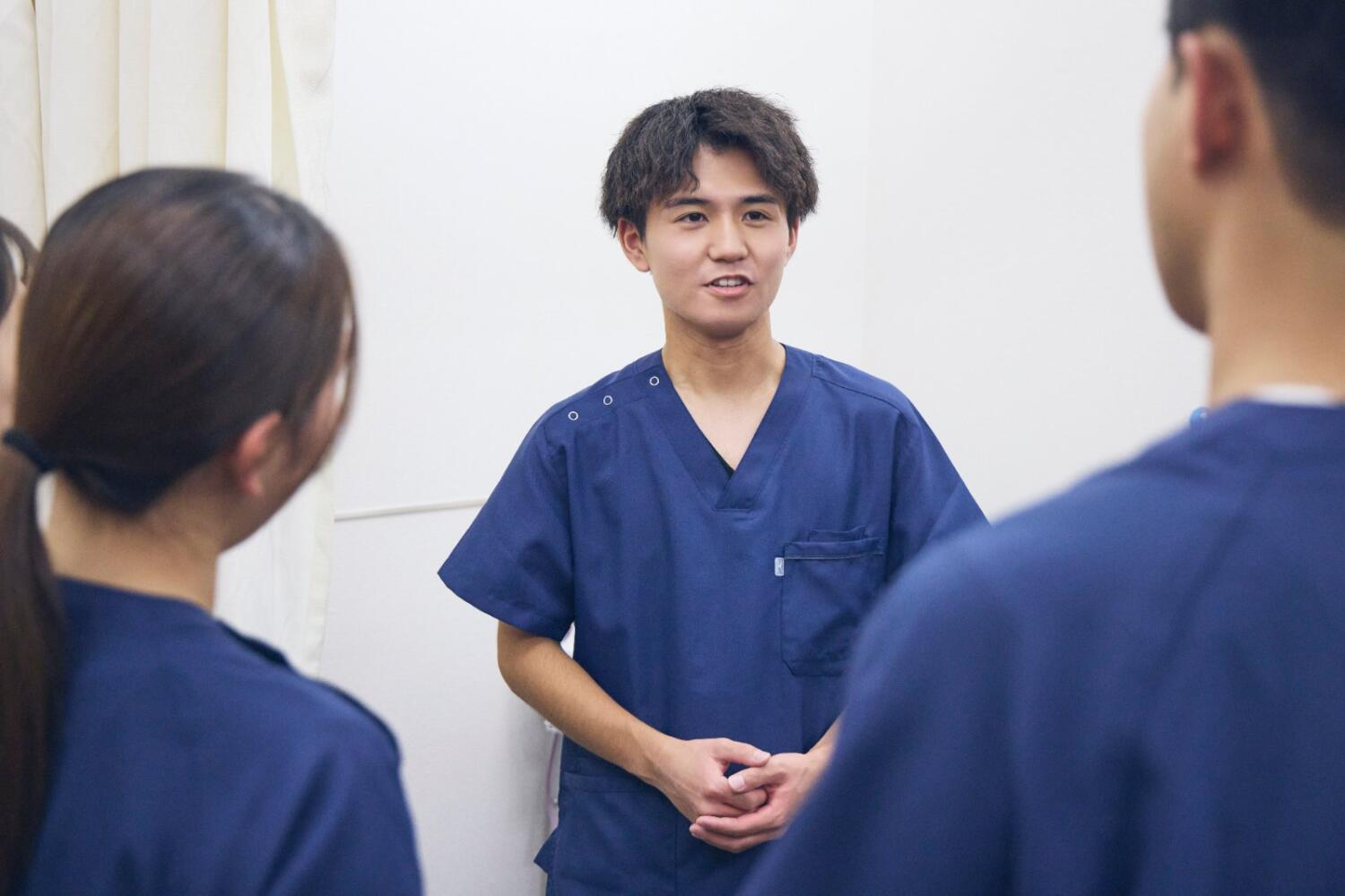 スクラブ姿の柔道整復師が仲間と笑顔で話している様子